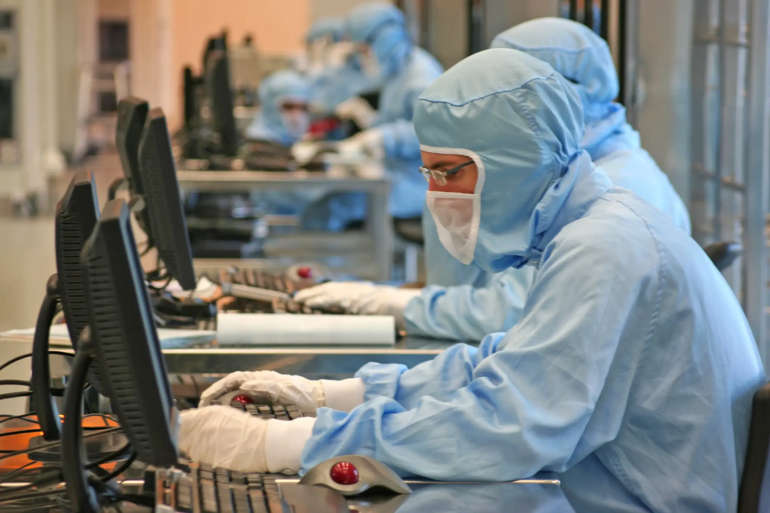 Gruppo di persone in abiti blu della ST Microelectronics che lavorano su computer.